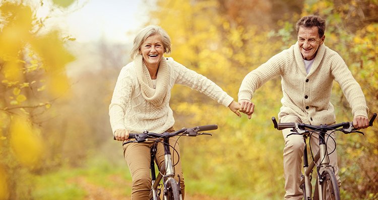 aging gracefully - active seniors riding bike in autumn
