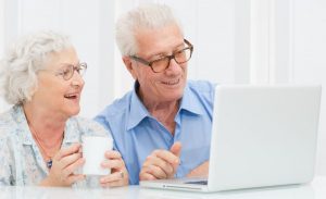 happy smiling retired couple using computer laptop at home